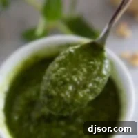 Fresh Basil Pesto 8 A spoonful of vibrant green basil pesto gracefully drizzled over a simple bowl.