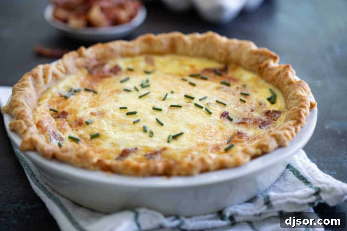 A Whole Quiche Lorraine: Golden, Flaky, and Irresistibly Savory A beautifully baked whole Quiche Lorraine nestled in a pie dish on a rustic kitchen towel, showcasing its golden crust and inviting appearance.