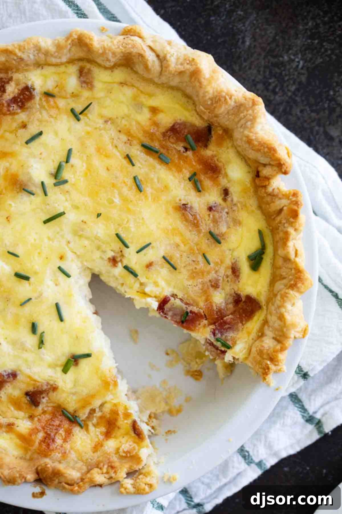 Perfectly Sliced Quiche Lorraine: A Culinary Delight An inviting overhead view of a freshly baked Quiche Lorraine with one slice already cut out, revealing the creamy custard, bacon, and cheese.