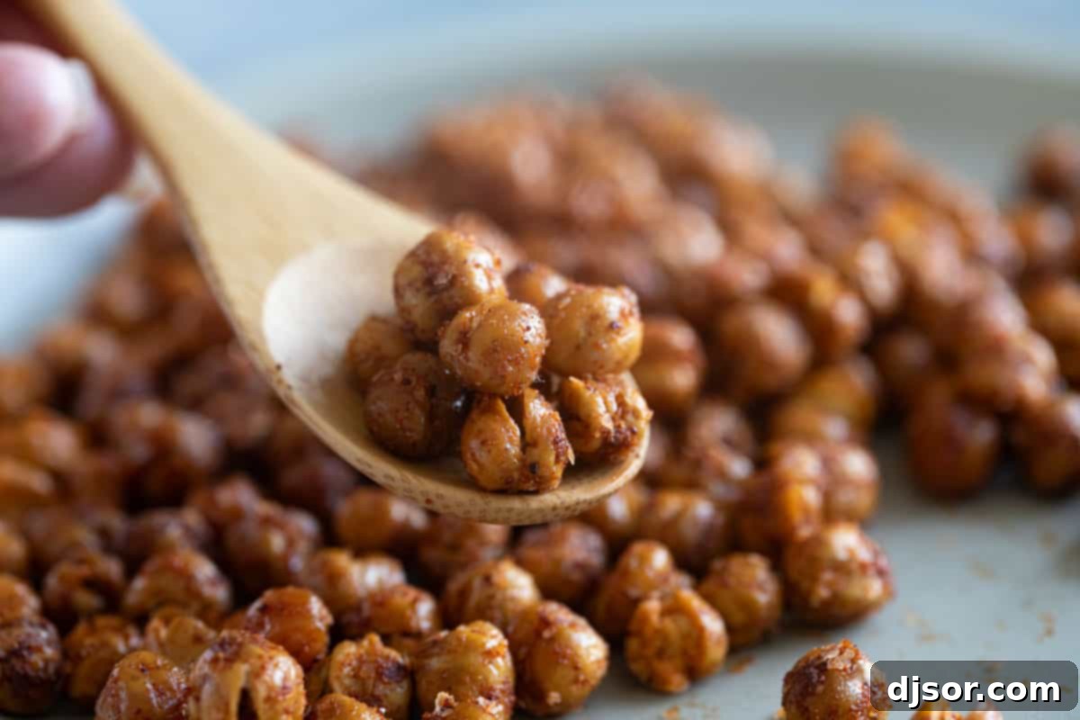 Spiced, oven-roasted chickpeas in a wooden spoon, showcasing their golden-brown crispiness.
