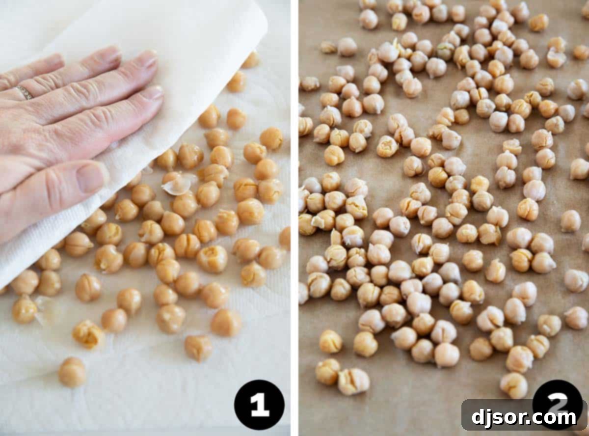 Hand gently rubbing rinsed chickpeas dry with a clean kitchen towel on a baking sheet, with some loosened skins visible.