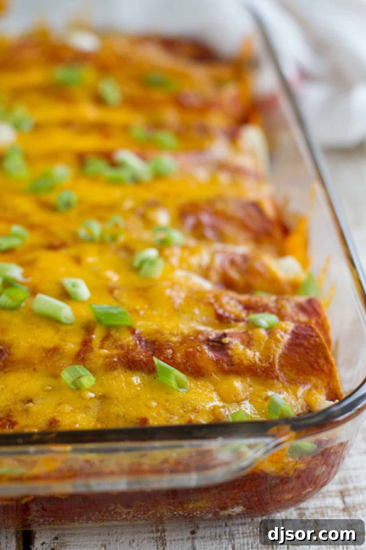 Cheesy Beef and Bean Enchiladas 2 A pan of delicious Beef and Bean Enchiladas, freshly baked and topped with melted cheese and rich red sauce, ready to be served.