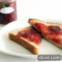 Close-up of a small glass jar filled with rich, red strawberry rhubarb jam, perfect for toast or gifting.