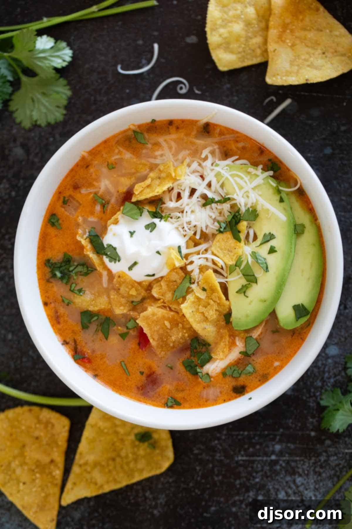 Cheesy Slow Cooker Chicken Enchilada Soup 8 Bowl of slow cooker chicken enchilada soup topped with tortilla chips, sour cream, and avocado.