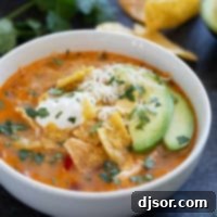 Cheesy Slow Cooker Chicken Enchilada Soup 9 Bowl of slow cooker chicken enchilada soup topped with cheese, tortilla chips, sour cream, cilantro, and avocado.