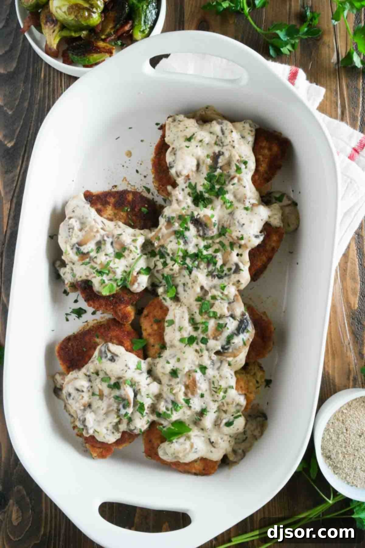 Italian Pork Chops in a Baking Dish with Creamy Mushroom Sauce overhead view of pork chops in a baking dish topped with gravy