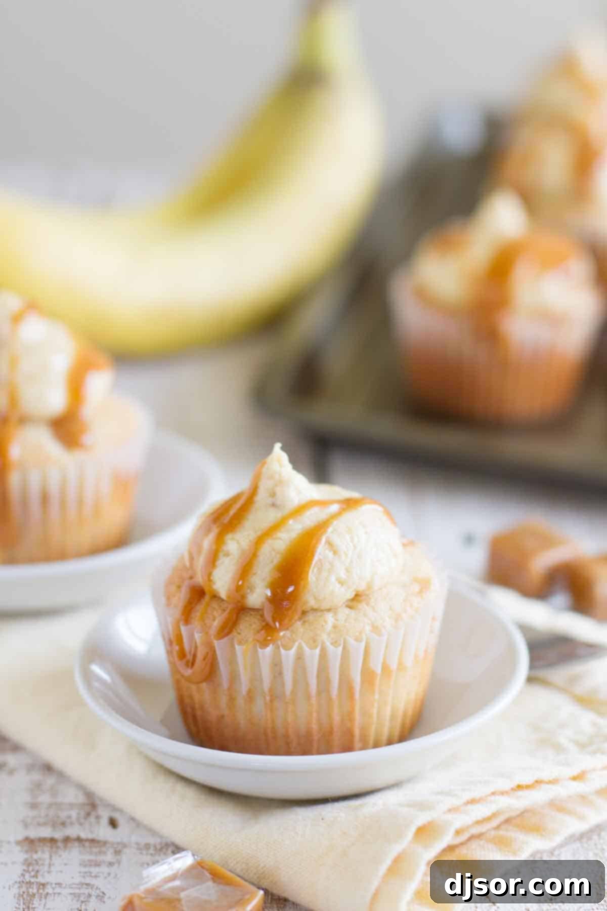 Decadent Caramel Banana Cupcakes drizzled generously with caramel sauce on an elegant plate, showcasing their rich texture and inviting appeal.