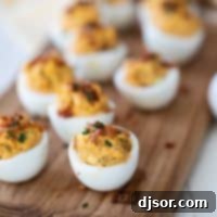 Smoky Bacon Deviled Eggs 2 Easy Deviled Eggs - Deviled Eggs with Bacon, garnished with fresh chives and crispy bacon bits, presented for serving.