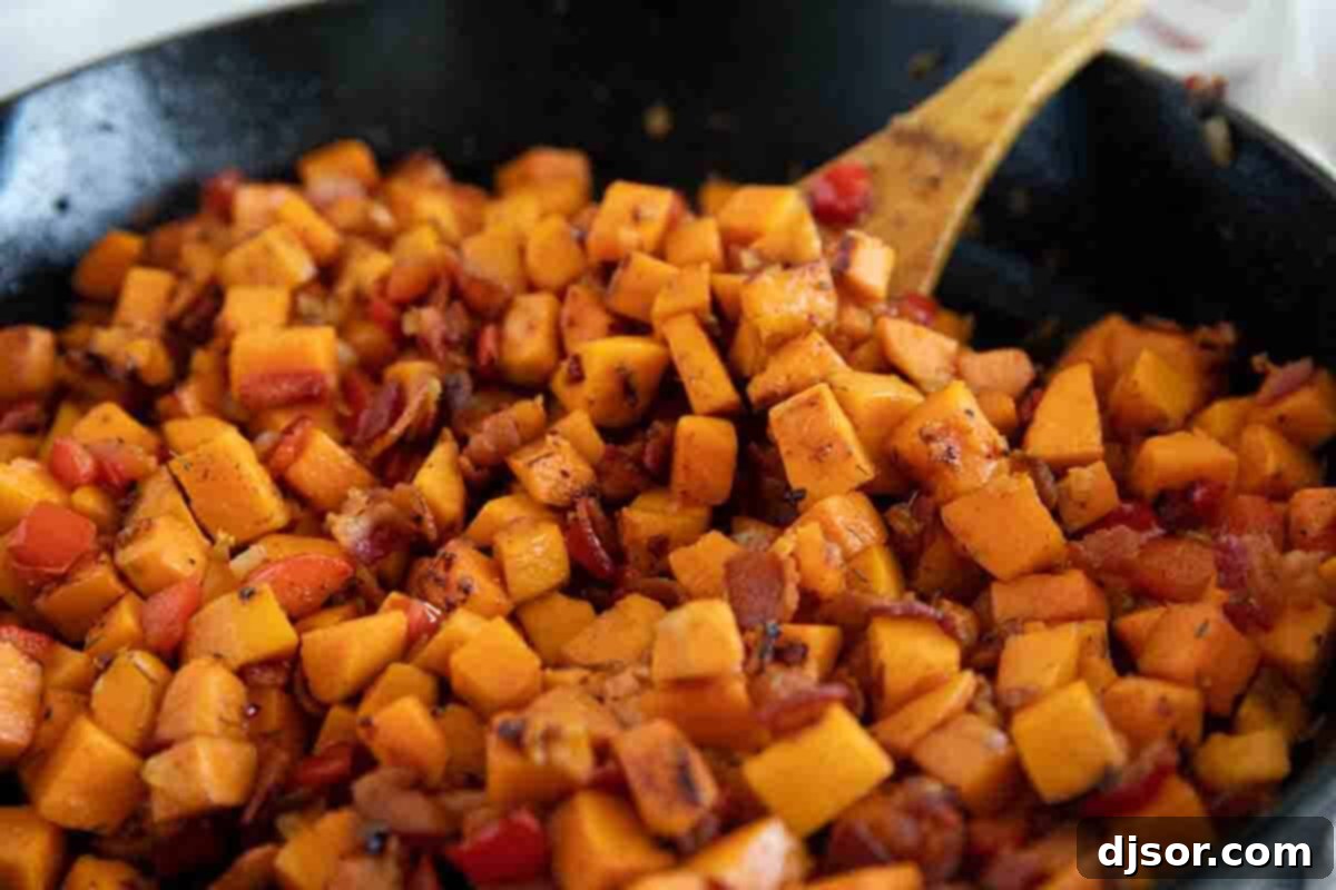 The perfect Sweet Potato Hash – sweet potatoes are combined with bacon, onions and sweet red peppers in this easy stovetop dish. Serve it as a side dish or add an egg on top and turn it into breakfast. Cast iron skillet filled with Sweet Potato Hash, featuring golden sweet potatoes, crispy bacon, and colorful bell peppers.