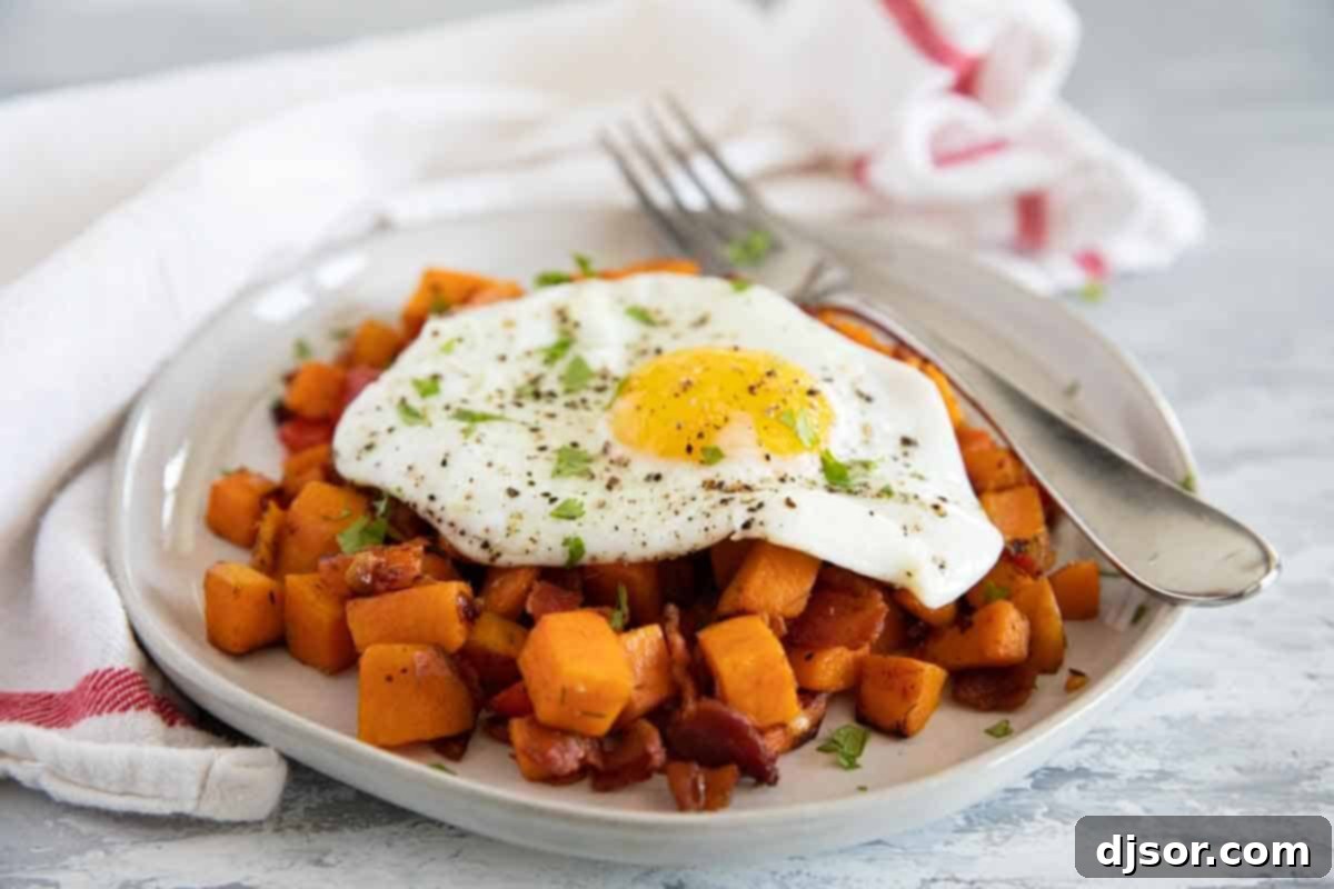 The perfect Sweet Potato Hash – sweet potatoes are combined with bacon, onions and sweet red peppers in this easy stovetop dish. Serve it as a side dish or add an egg on top and turn it into breakfast. A plate of Sweet Potato Hash topped with a perfectly cooked over easy egg and a sprinkle of fresh herbs, ready for a delicious breakfast.