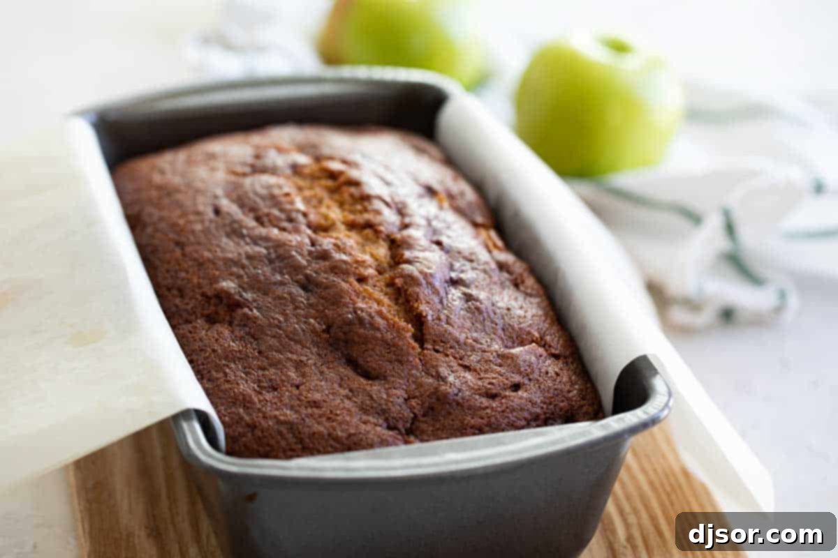 Autumn Pumpkin Apple Loaf 4 Baked pumpkin apple bread in a loaf pan, with fresh apples beside it.