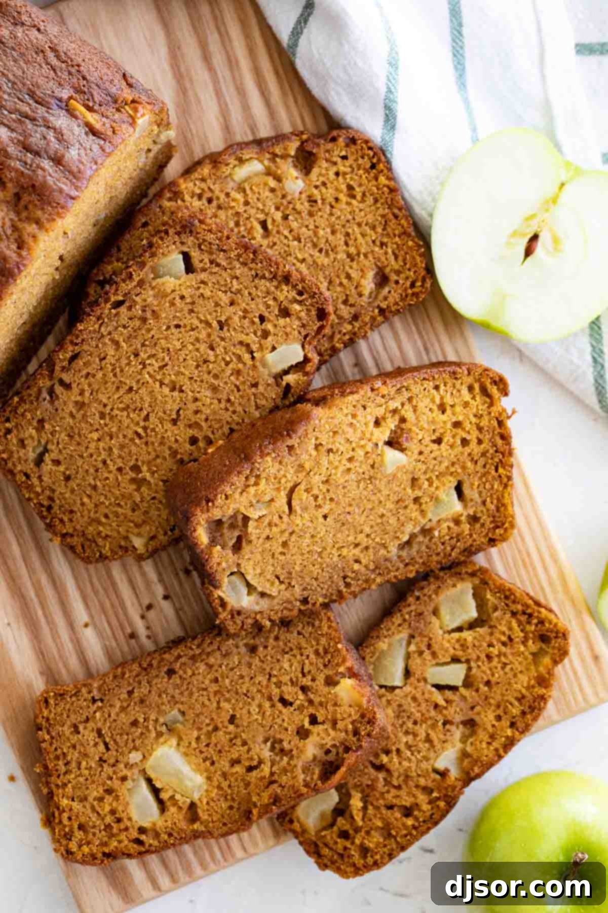 Autumn Pumpkin Apple Loaf 5 Overhead view of several slices of pumpkin apple bread on a cutting board, with fall decor.
