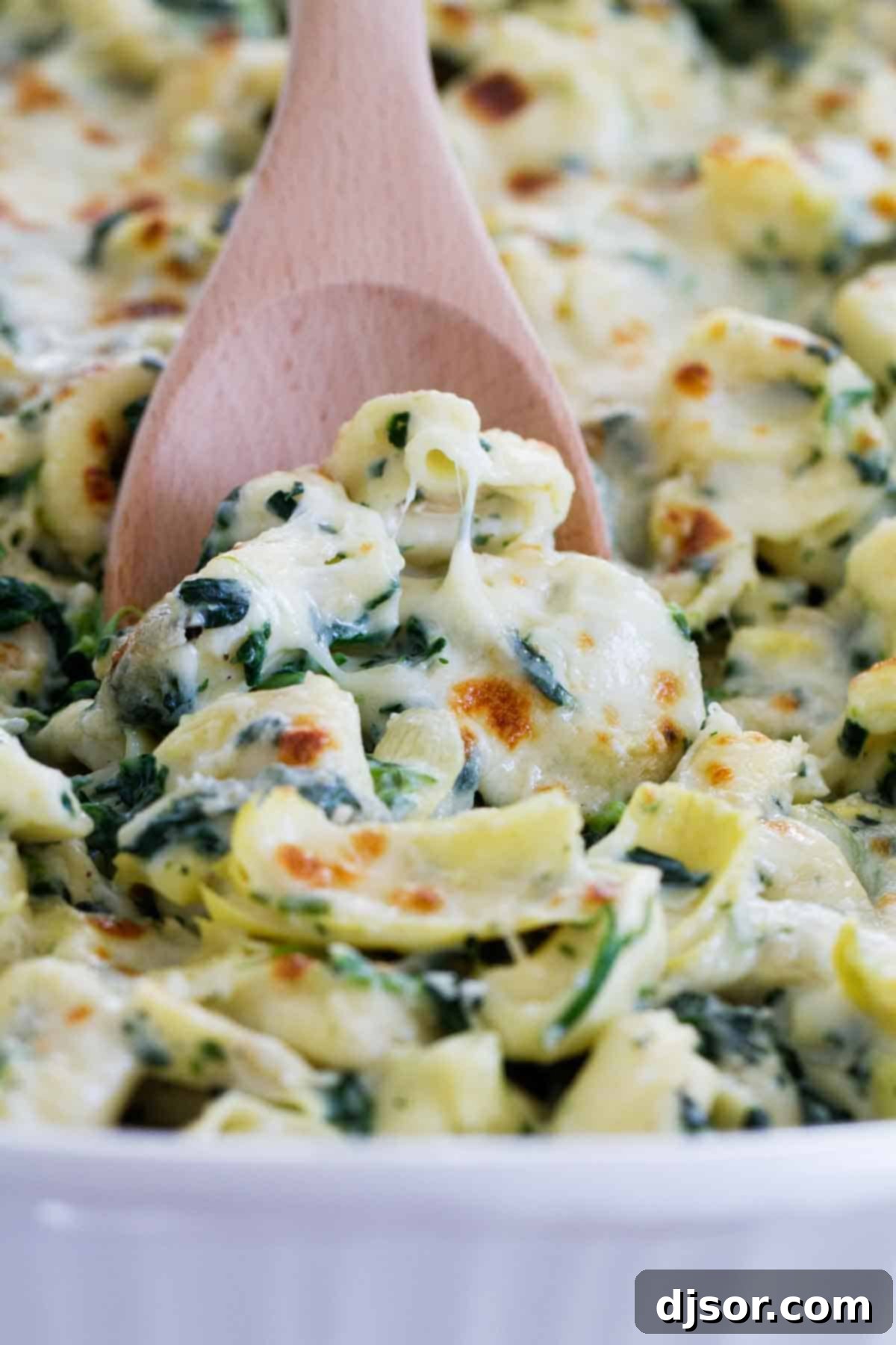 A large baking dish filled with cheesy Spinach and Artichoke Tortellini Bake, fresh out of the oven, ready to be served.