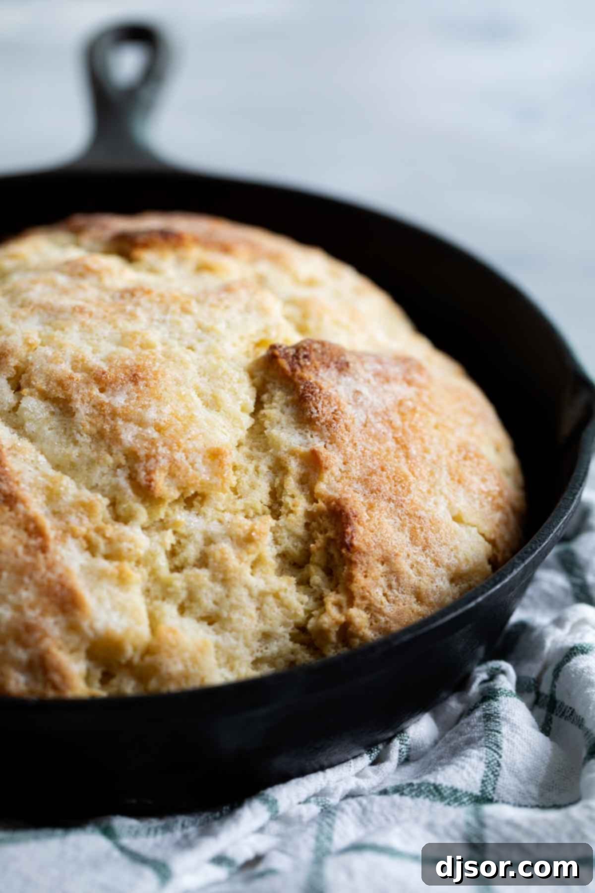 A freshly baked, rustic Irish Soda Bread loaf cooling in a cast iron pan, ready to be sliced.
