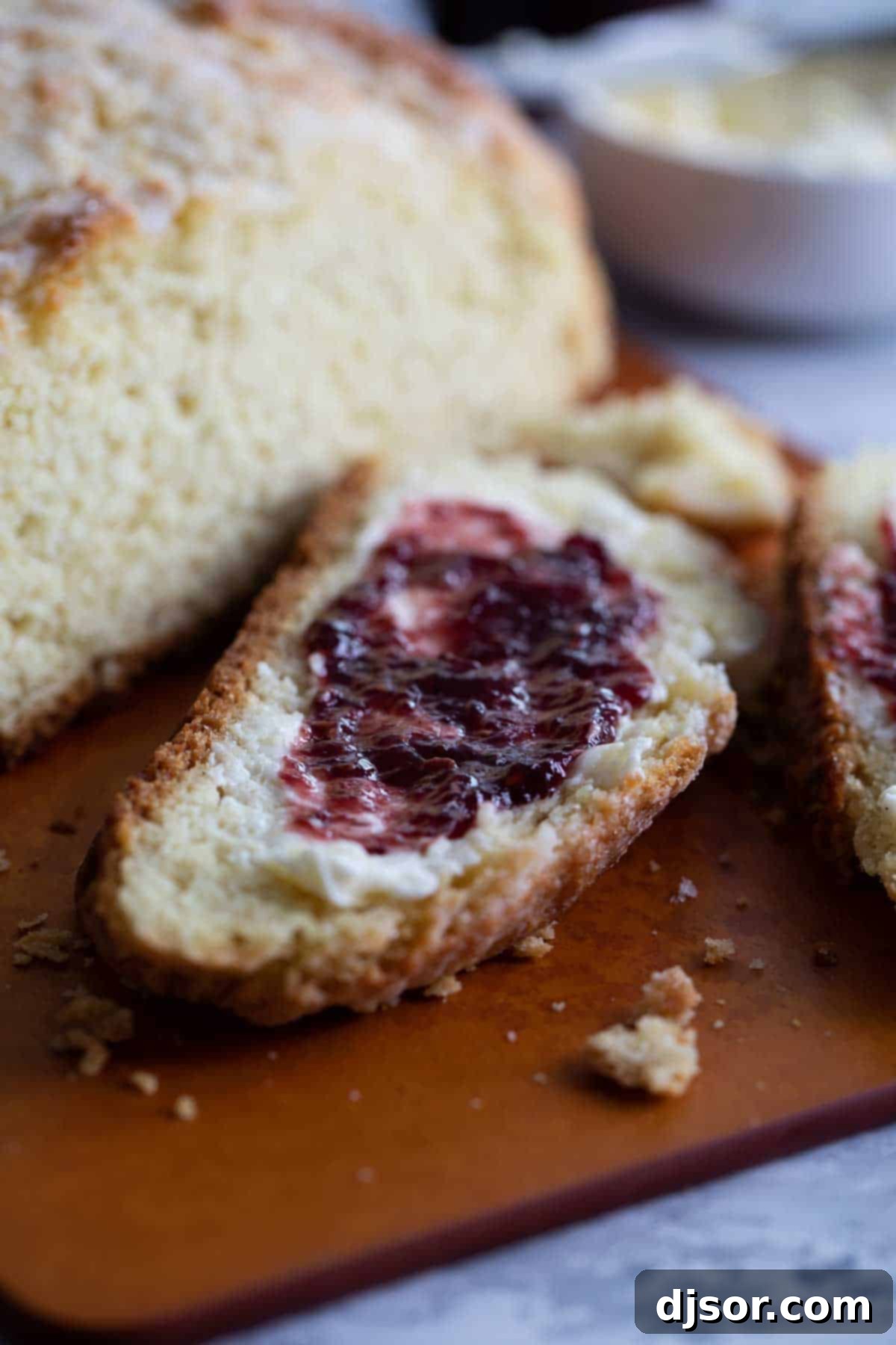 A slice of Irish Soda Bread topped with a generous dollop of fruit jam, invitingly presented.