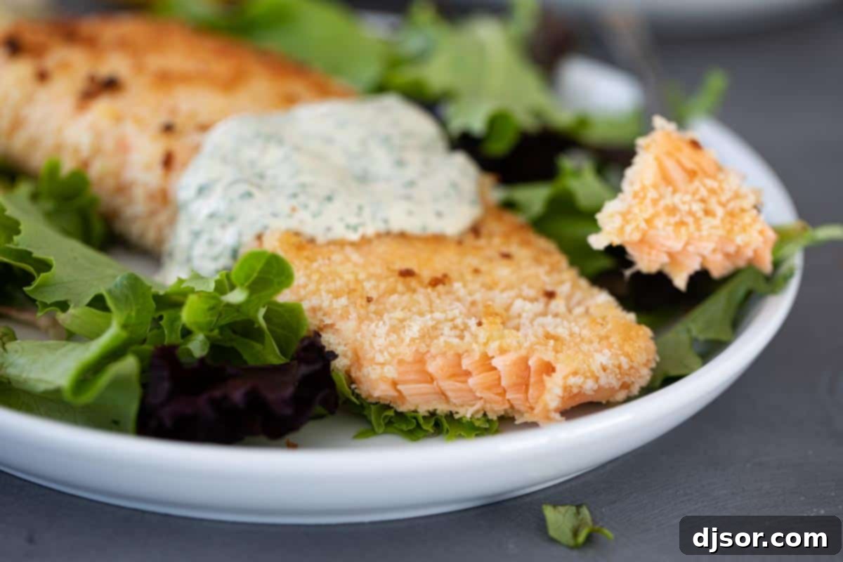 An easy weeknight dinner, this Pan Fried Salmon with Remoulade looks fancy but is super simple! Panko crusted salmon is cooked on the stovetop with a simple, flavorful sauce. Detailed shot of the crispy, golden-brown panko crust on pan-fried salmon, showcasing its inviting texture.