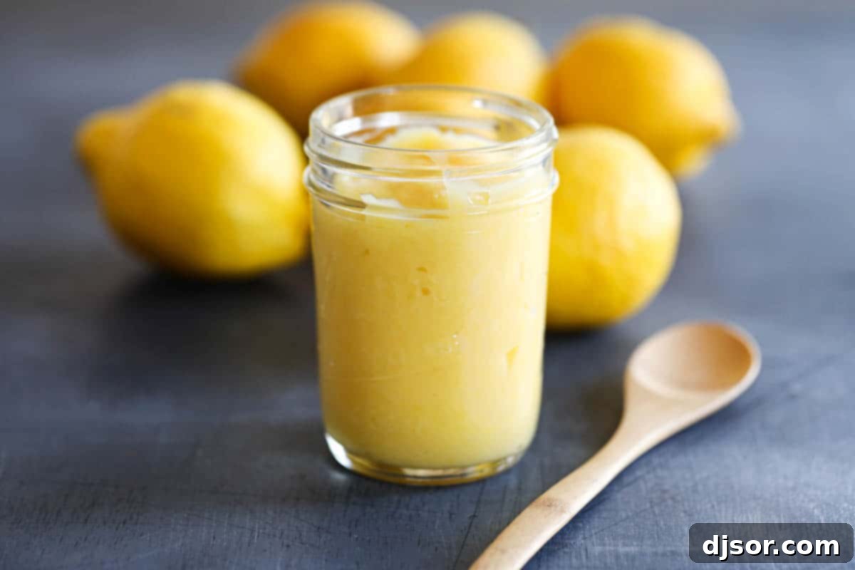 jar of lemon curd with a wooden spoon and lemons in the background