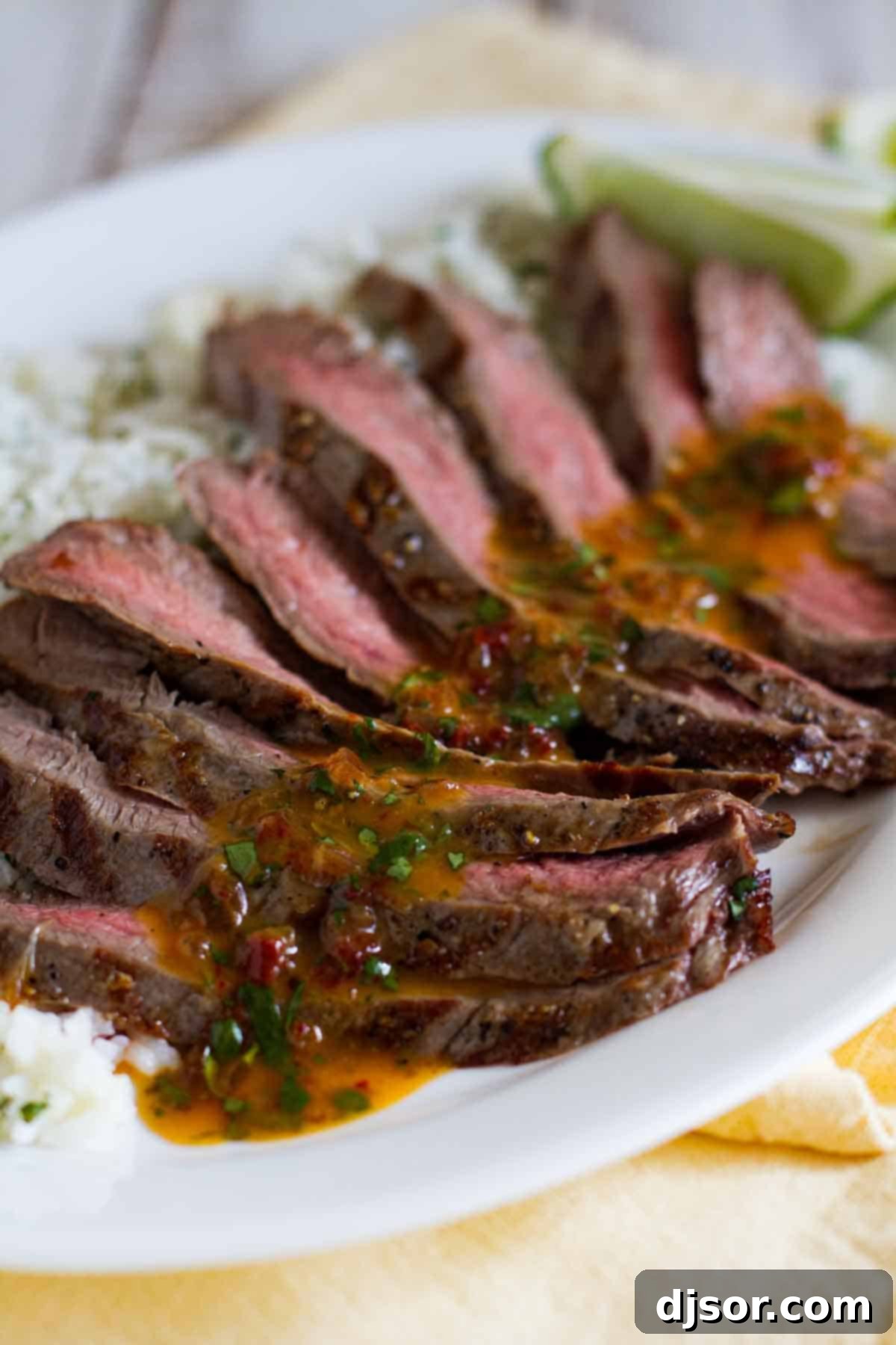 Perfectly sliced Chipotle Herb Flank Steak served over a bed of cilantro rice on a rustic platter.