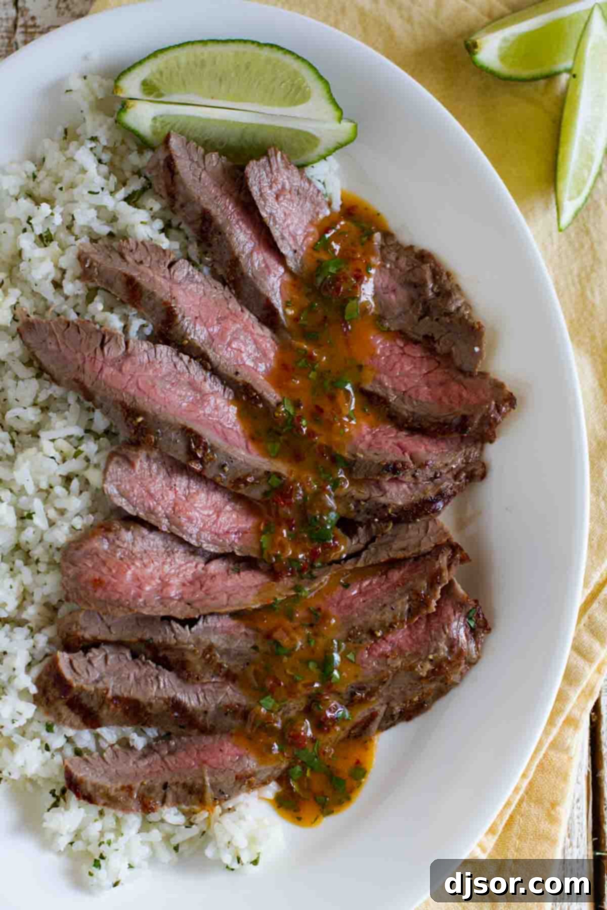Close-up overhead view of tender, juicy slices of Chipotle Herb Flank Steak drizzled with melted chipotle butter, showcasing the perfect medium-rare doneness and vibrant grill marks.