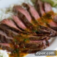 sliced flank steak with chipotle butter over rice on a platter