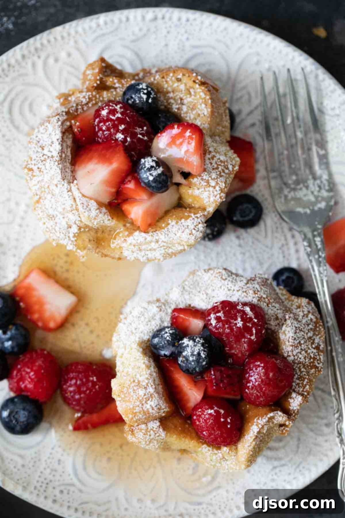 overhead view of individual french toast with berries and syrup