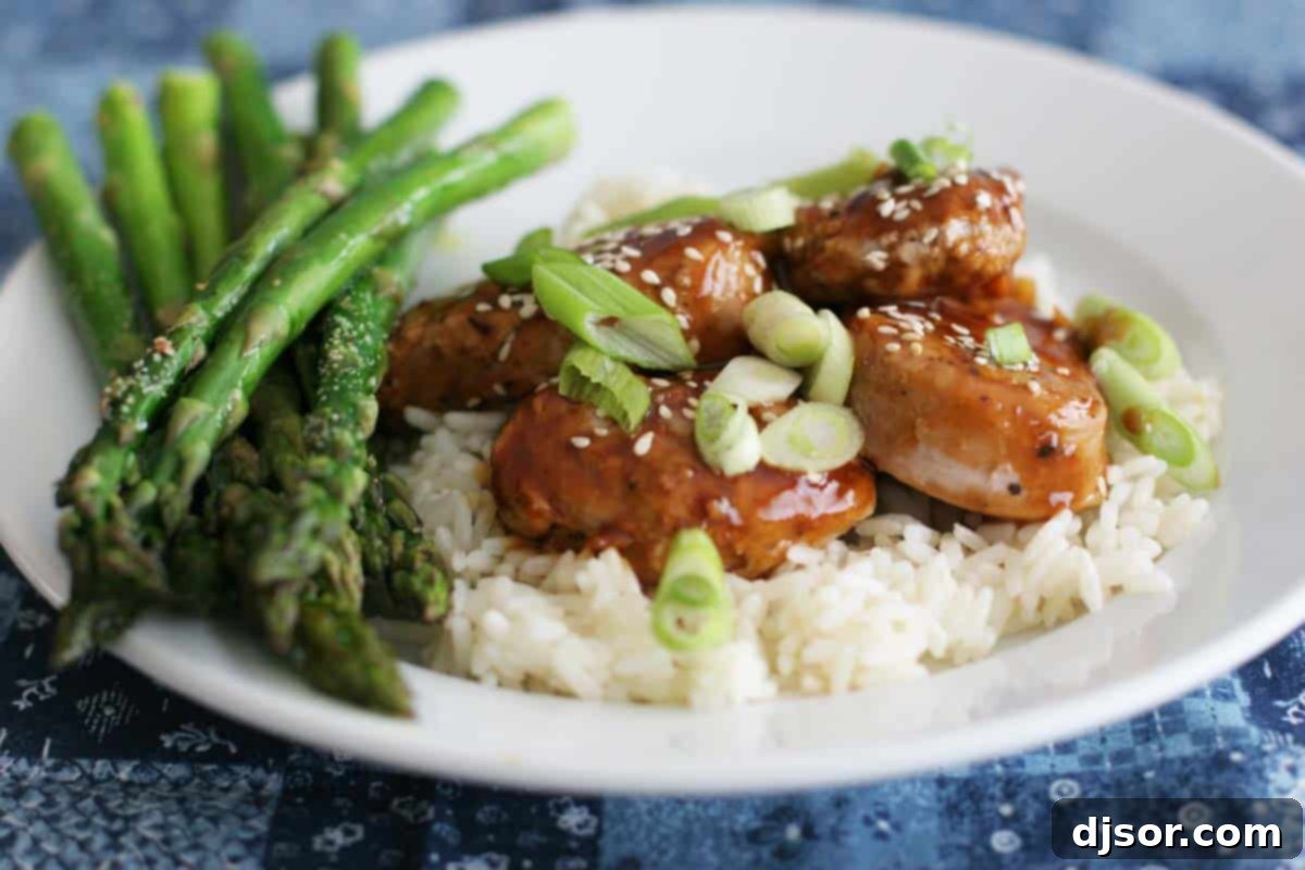 Easy Pork with Hoisin Sauce served over rice with steamed asparagus, garnished with sesame seeds and green onions.