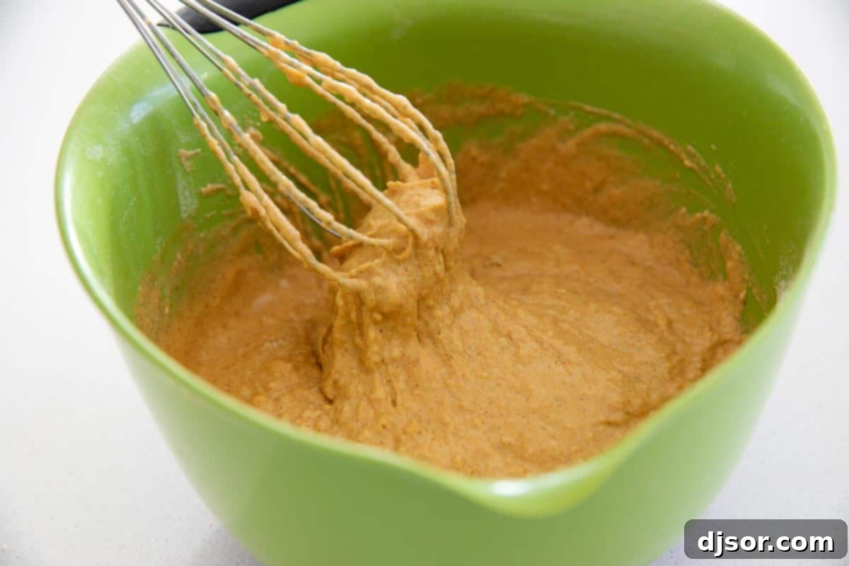 Close-up view of thick, spiced pumpkin pancake batter in a bowl, showing its rich color and smooth consistency before cooking.
