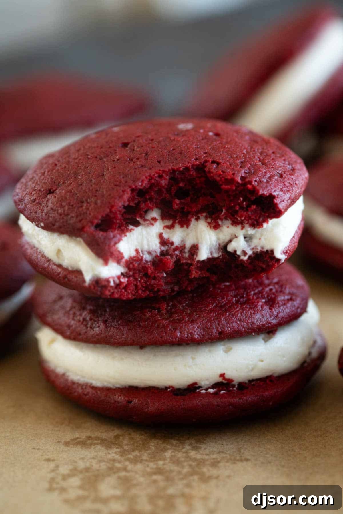 Two perfectly made Red Velvet Whoopie Pies, stacked invitingly on top of each other, showcasing their delightful texture and rich color.