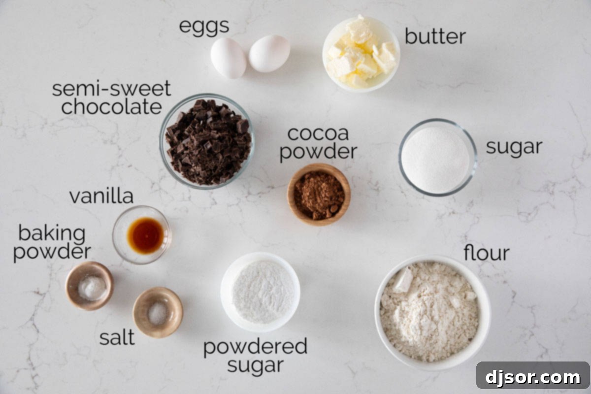 Various ingredients for Chocolate Crinkle Cookies laid out on a table, including chocolate bars, butter, sugar, eggs, flour, cocoa powder, and powdered sugar.