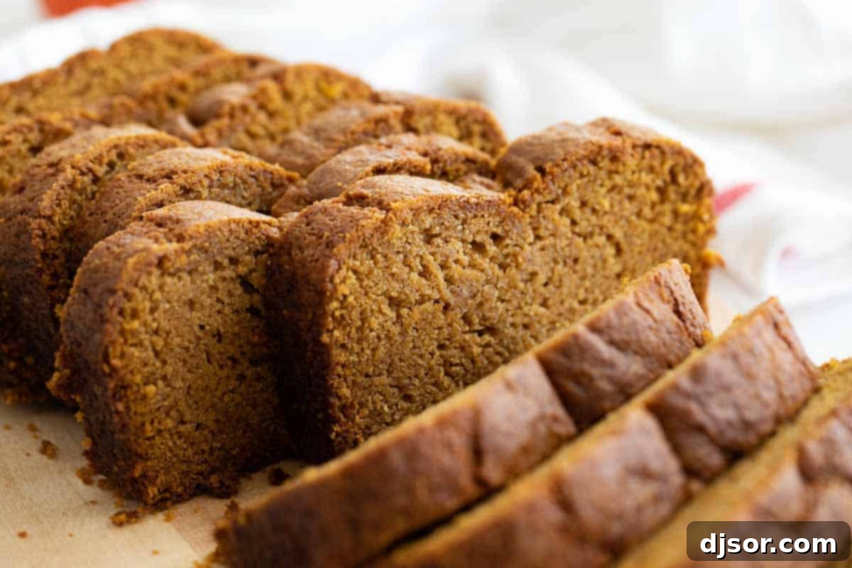 A beautifully sliced loaf of moist pumpkin bread, showcasing its rich orange color and delicate texture, ready to be enjoyed.