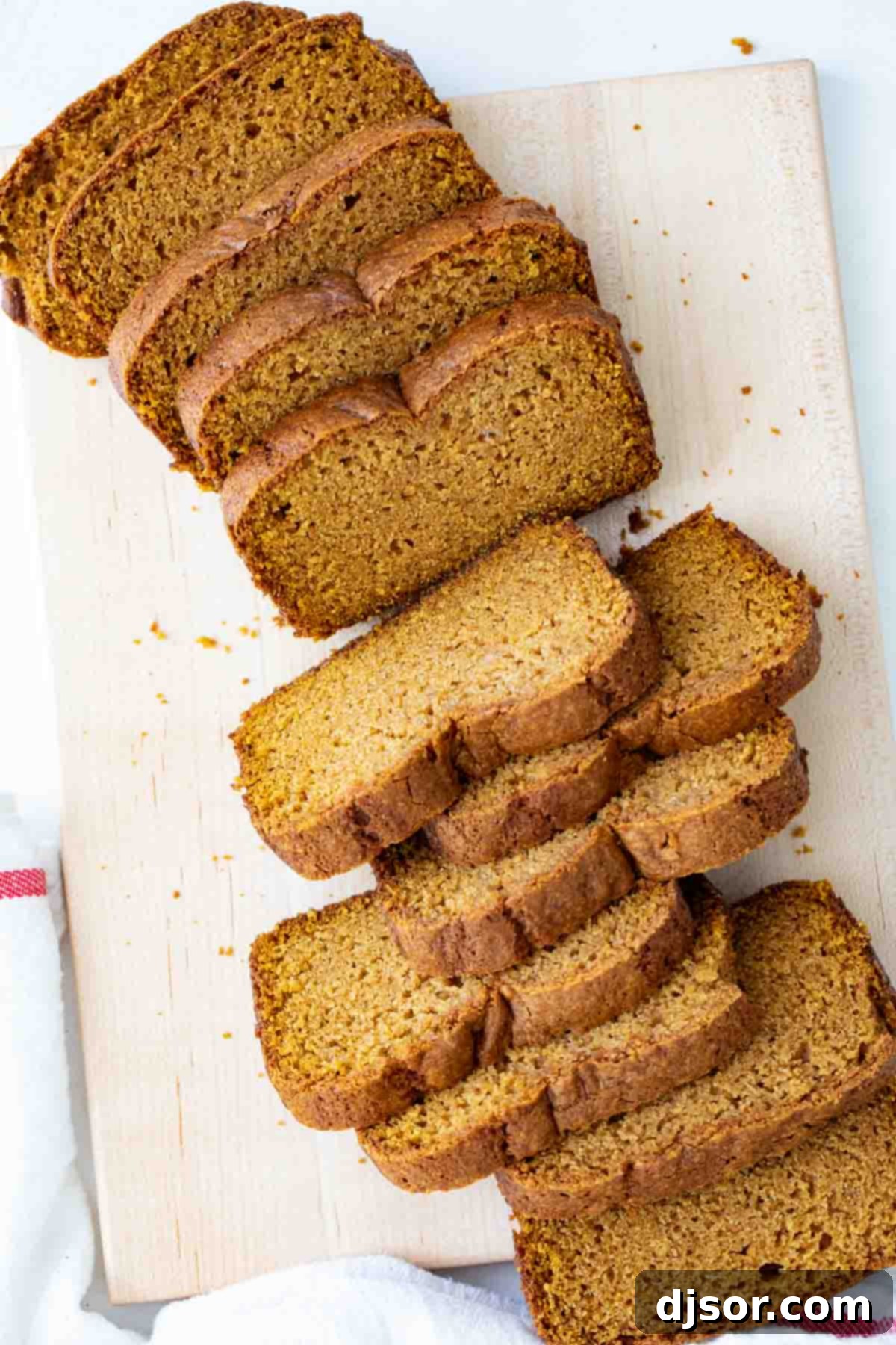 An overhead view of a perfectly baked and sliced pumpkin bread on a wooden cutting board, ready to be served.