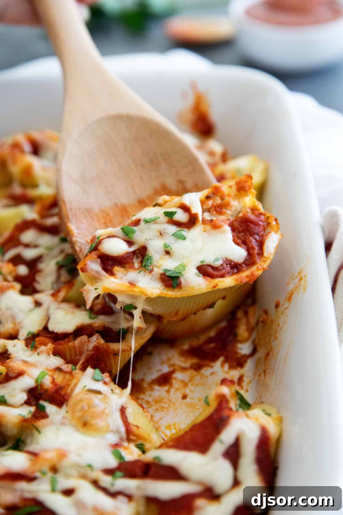 Serving of Chicken Stuffed Shells in a Baking Dish with a Wooden Spoon