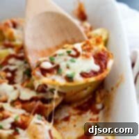 Stuffed Shell in baking dish with wooden spoon scooping out