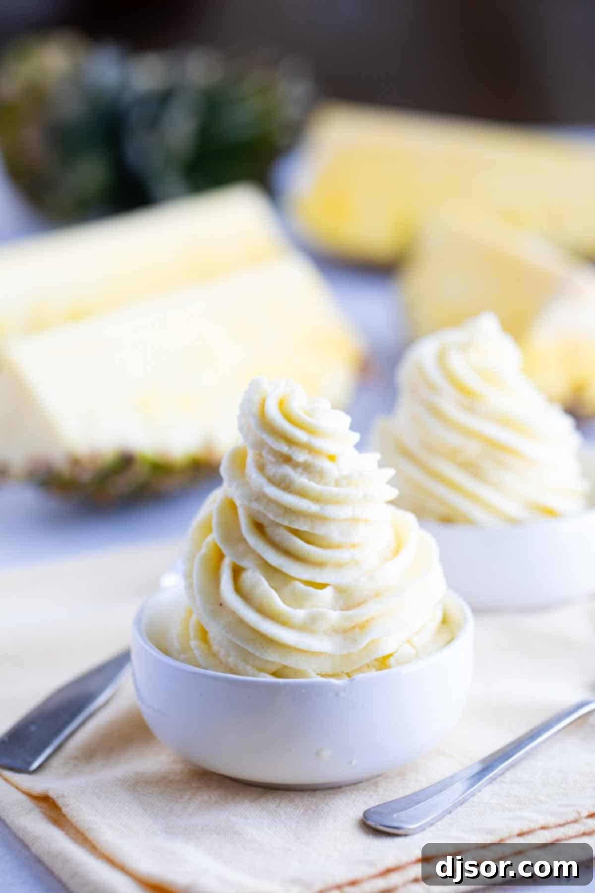 Two perfectly swirled bowls of homemade Dole Whip, ready to be enjoyed, showcasing a beautiful texture.