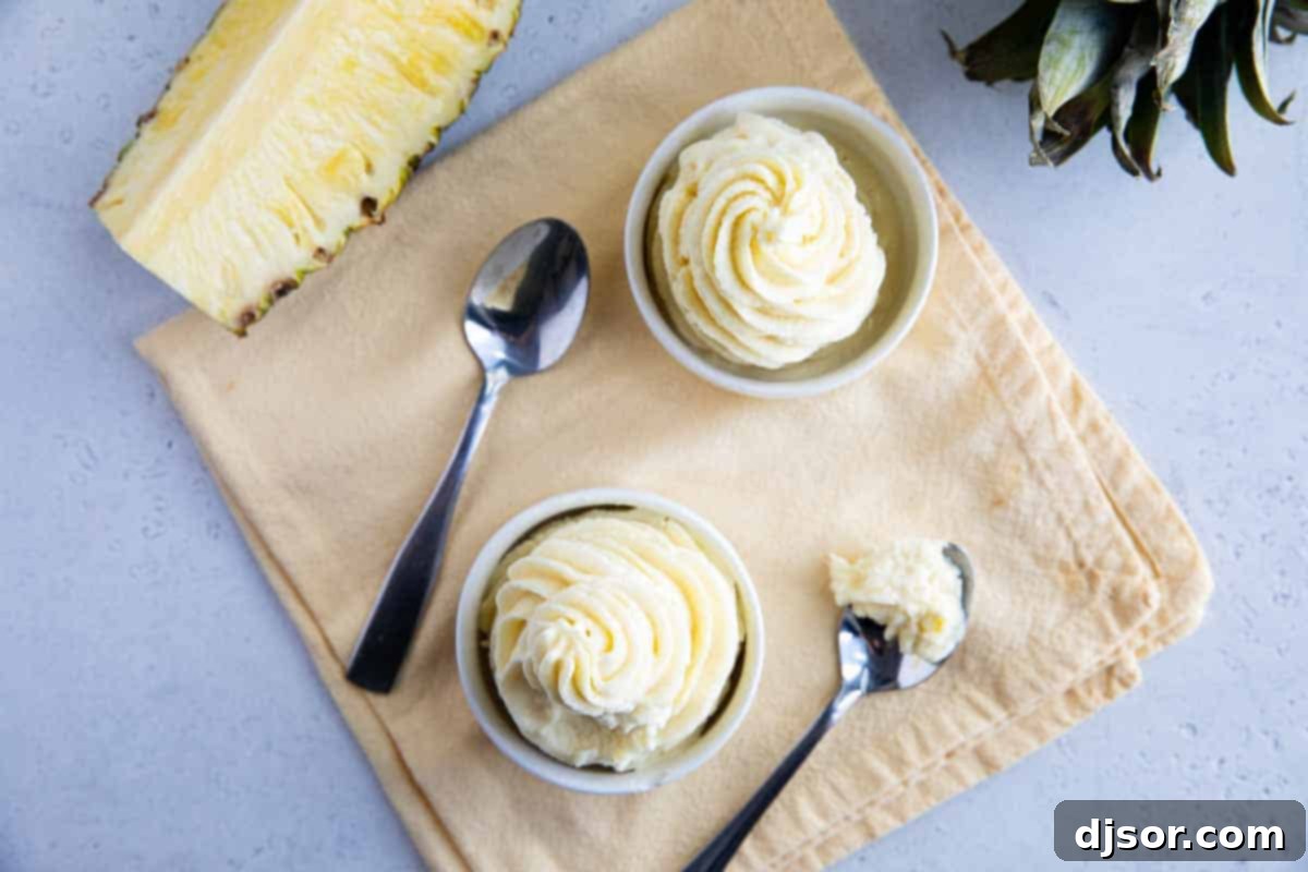 Two bowls of homemade Dole Whip, one with a spoon, showing a bite taken, highlighting the smooth and creamy texture.