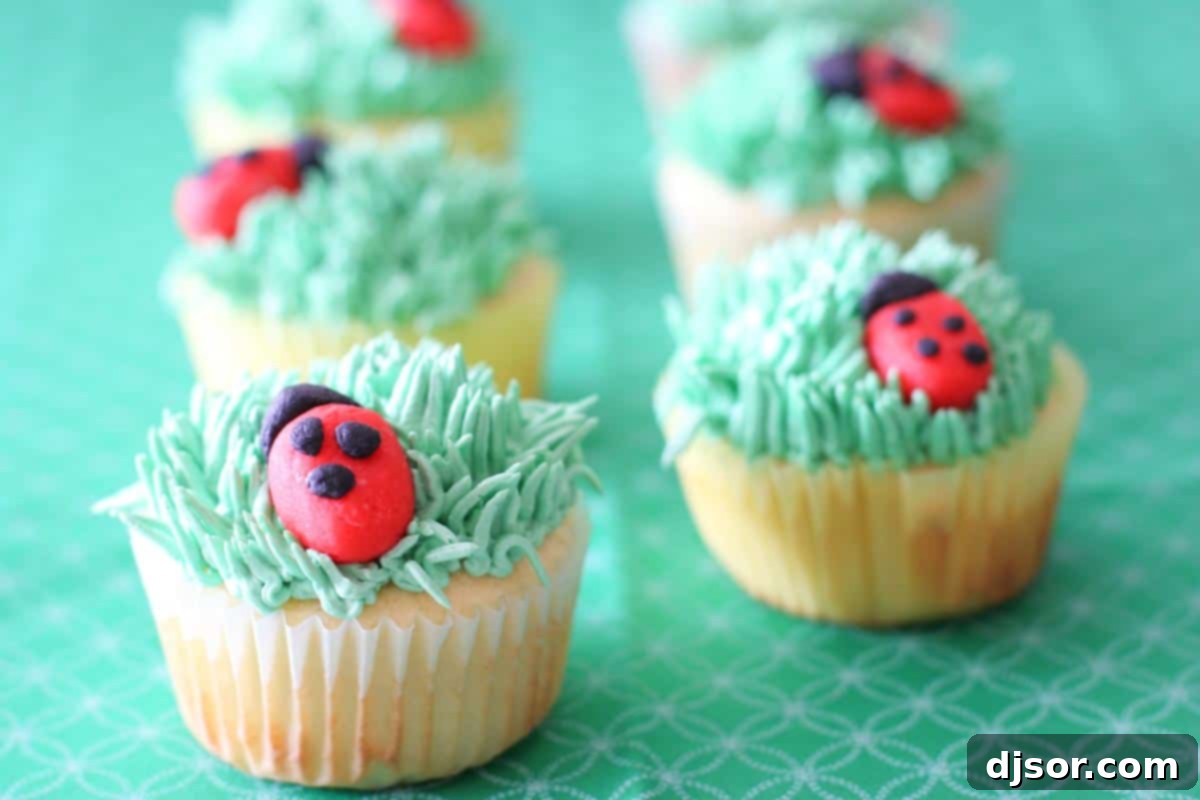 Delicious Ladybug Cupcakes with green buttercream grass and red marzipan ladybugs, perfect for spring or summer gatherings.