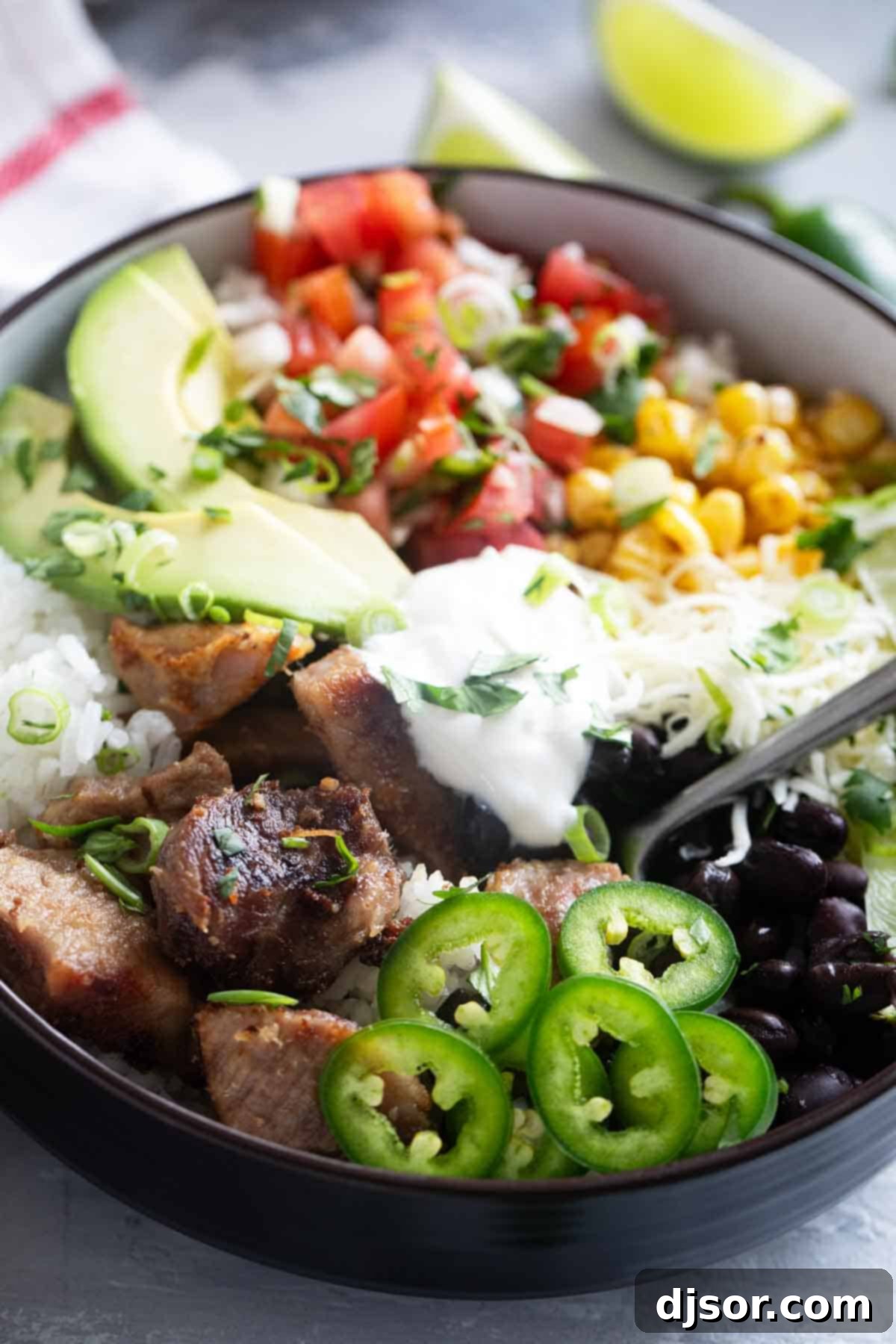 A close-up of a delicious Pork Carnitas Burrito Bowl with a fork plunged into it, ready to be savored, highlighting the rich textures and colors of the ingredients.