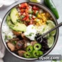 A close-up shot of a beautifully assembled Pork Carnitas Burrito Bowl, showcasing the golden-brown carnitas, fresh pico de gallo, melted cheese, and a swirl of sour cream, ready to be enjoyed.