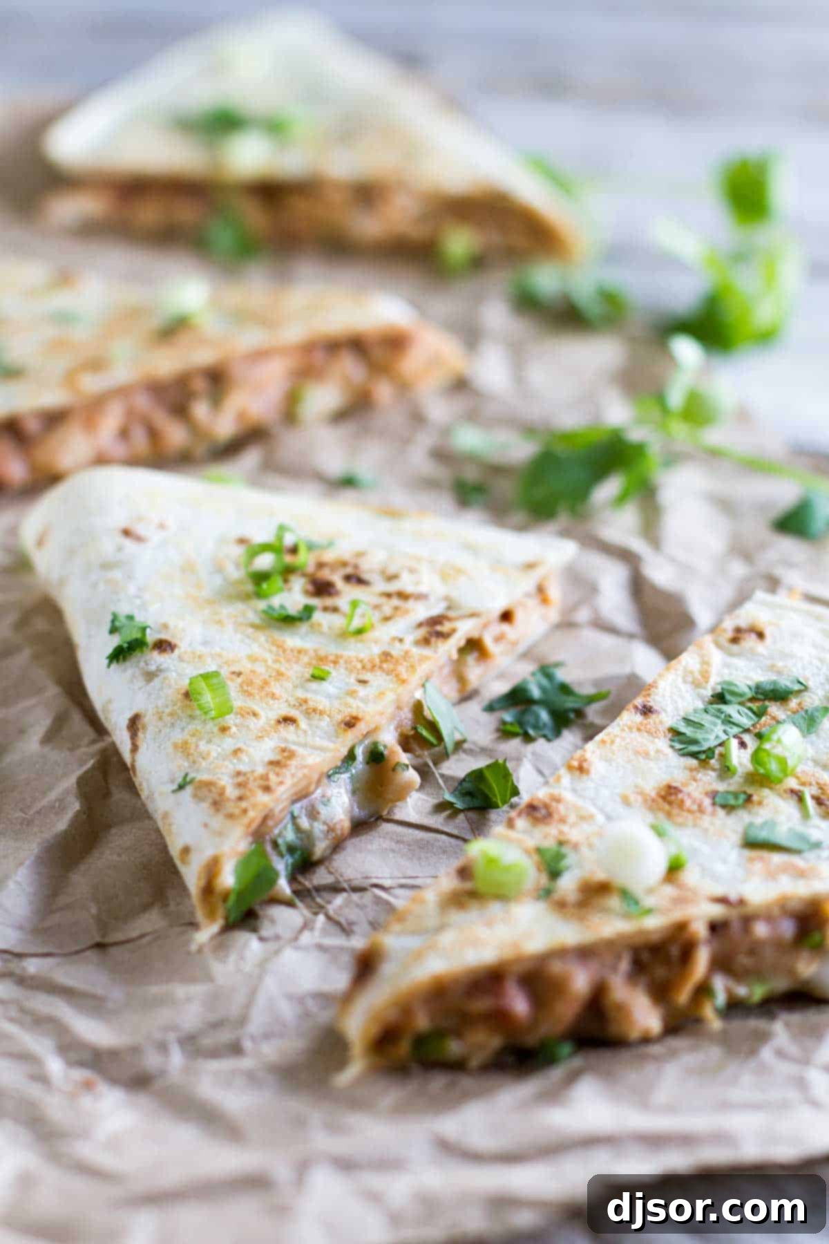 Golden-brown wedges of Chicken Quesadilla with Refried Beans, garnished with fresh cilantro, ready to be enjoyed.