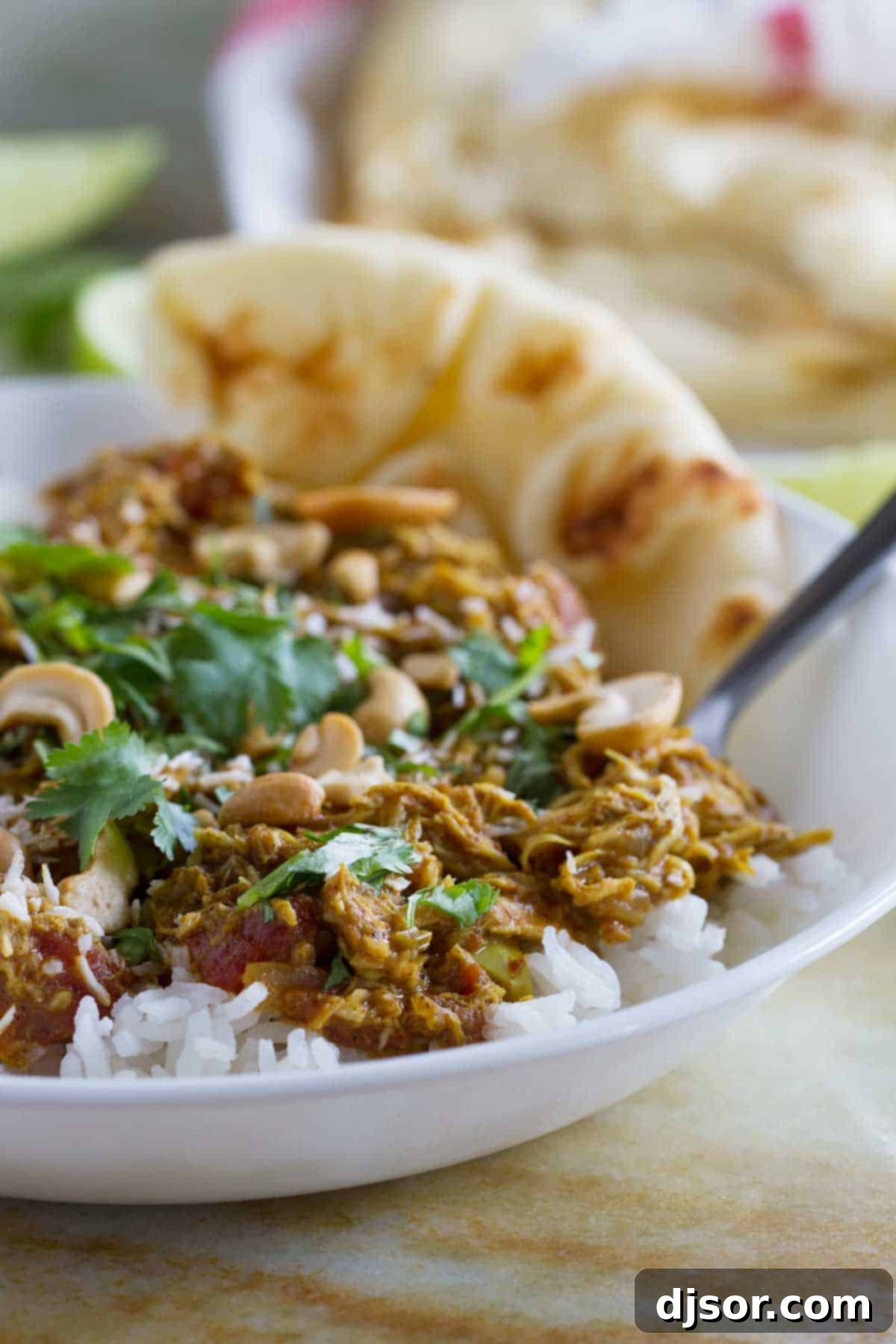 A vibrant bowl of Coconut Curry Chicken served over fluffy white rice, garnished with fresh cilantro.
