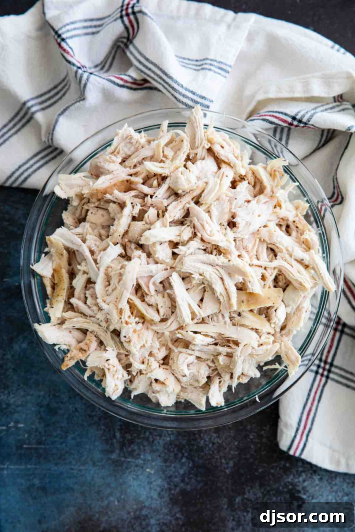 A large, inviting bowl filled with perfectly cooked and finely shredded chicken, ready for any recipe or meal prep.