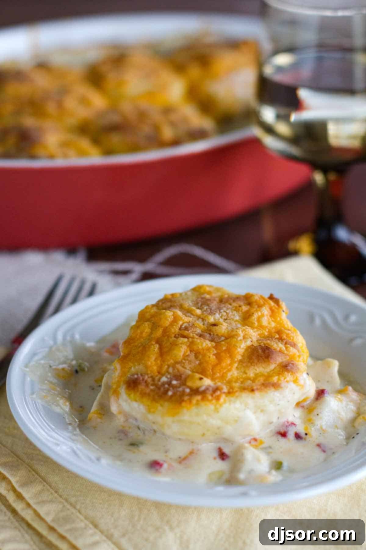 A generous serving of creamy Chicken and Biscuits in a shallow bowl, highlighting the tender biscuits and rich gravy.