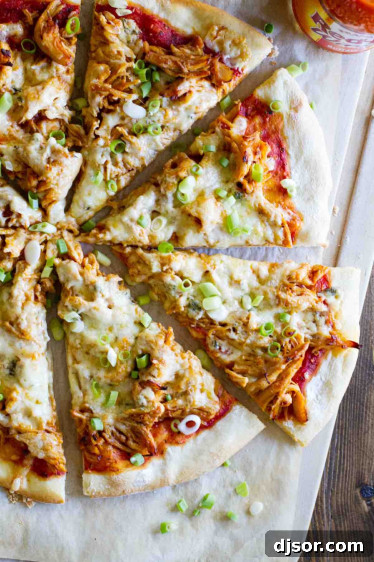 A vibrant Buffalo Chicken Pizza, generously topped with melted Monterey Jack cheese, crumbled blue cheese, and fresh green onions.