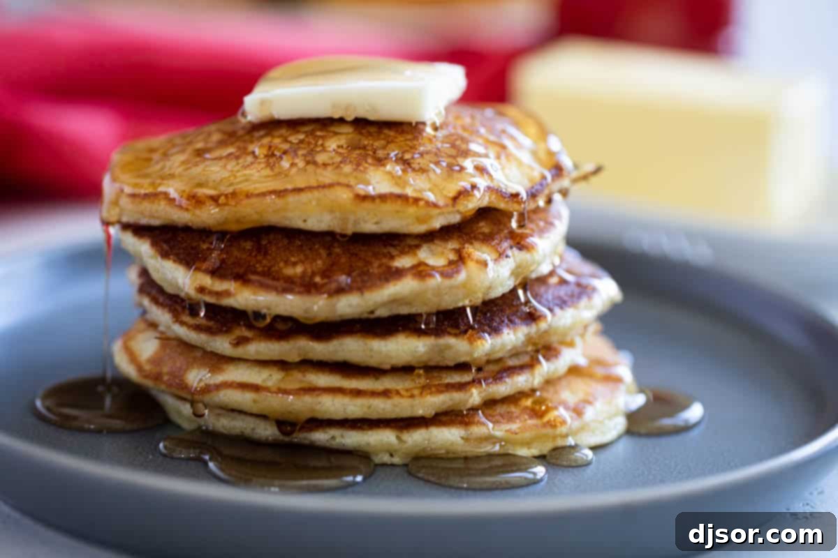 Delicious Cornmeal Pancakes with Butter and Syrup A tall stack of golden brown cornmeal pancakes, generously topped with a melting pat of butter and drizzled with rich maple syrup.