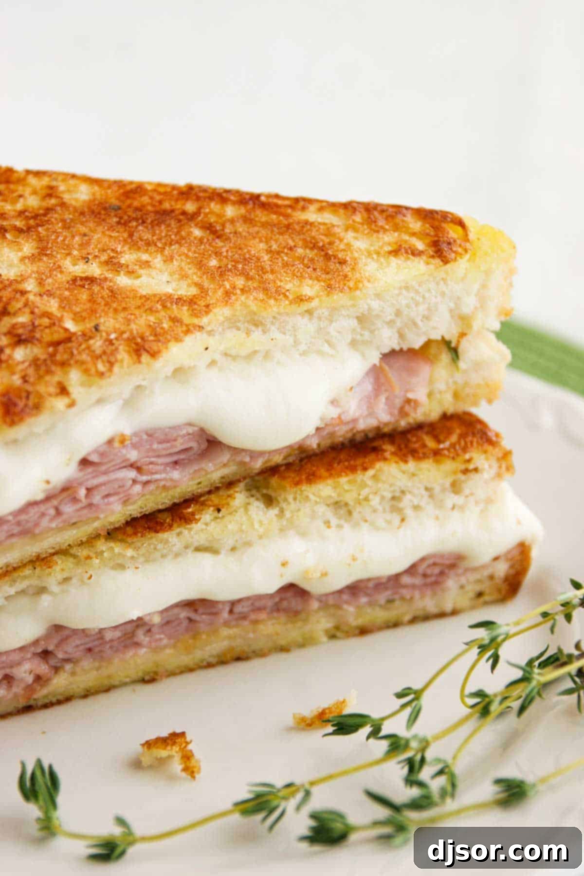 Tuscan Monte Cristos 3 Italian Style Monte Cristo with honey mustard thyme sauce cut in half, revealing layers of ham and melted mozzarella.