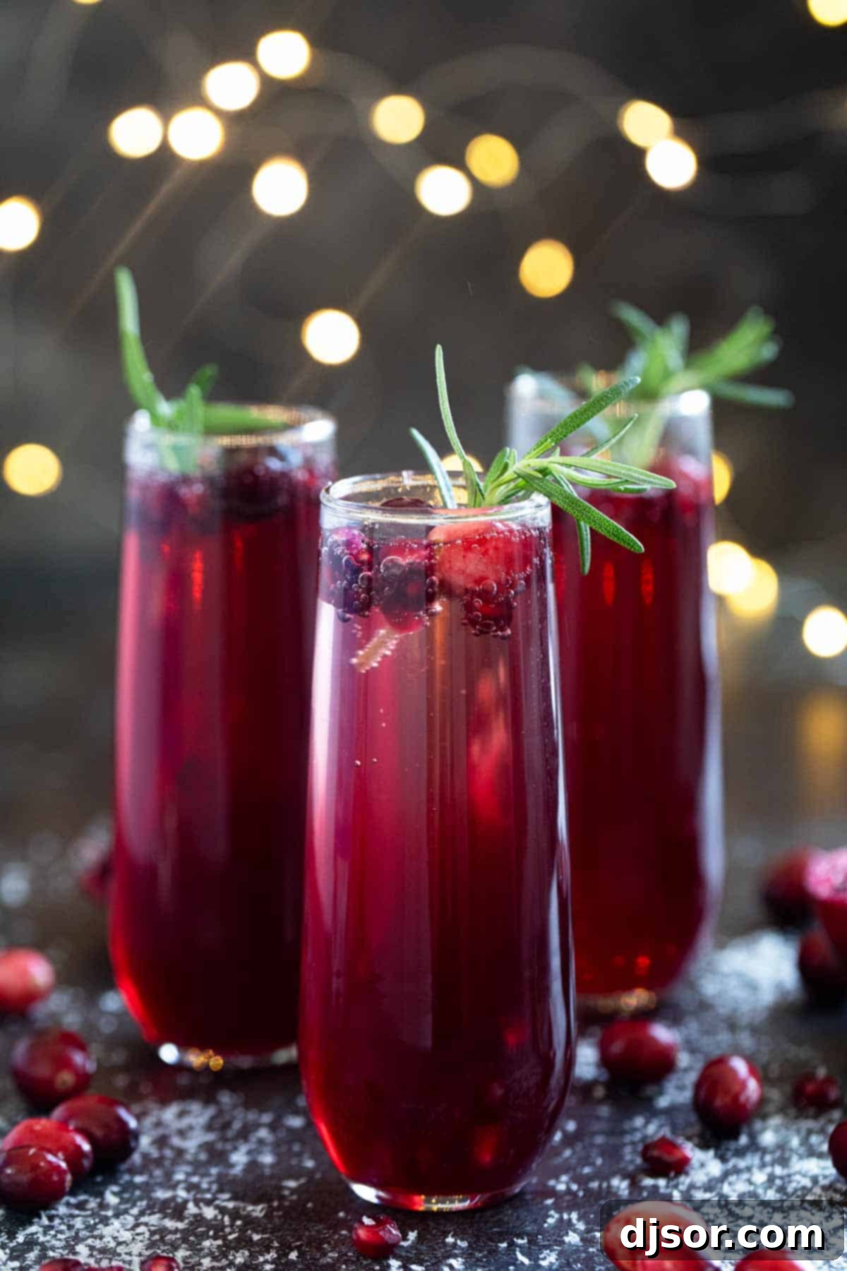 Crimson Pomegranate Cranberry Fizz 2 Three glasses of Virgin Pomegranate and Cranberry Bellini, garnished with fresh cranberries and rosemary.