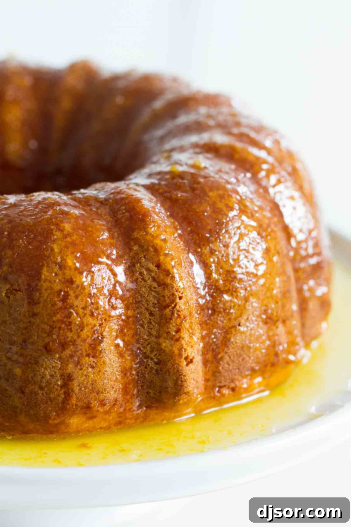 A vibrant orange cake with a glistening orange glaze, elegantly presented on a platter, ready to be served.
