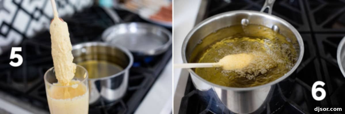 Close-up of a hot dog being carefully dipped into a tall cup of corn dog batter