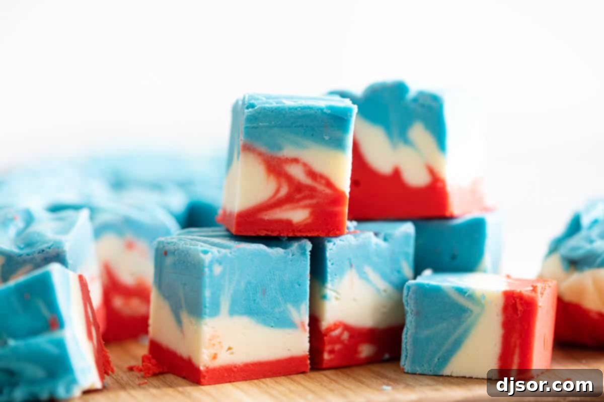Experience the joy of this unique 4th of July White Chocolate Fudge, featuring a stunning tie-dye pattern in red, white, and blue. A delicious and eye-catching patriotic dessert. Stacked pieces of Tie-Dyed 4th of July White Chocolate Fudge, showcasing the vibrant red, white, and blue swirls, perfect for a patriotic celebration.