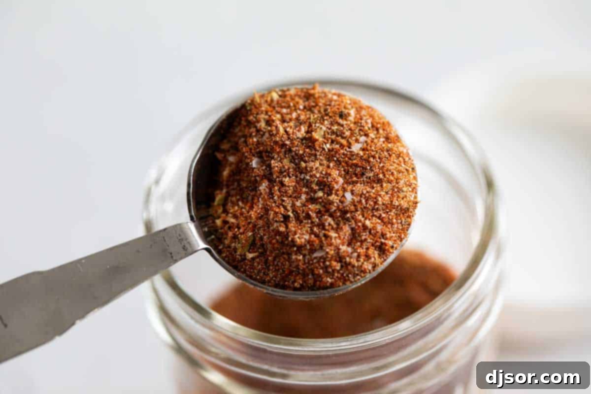 A tablespoon heaped with a rich, reddish-brown homemade Cajun spice blend, ready to be used in cooking.